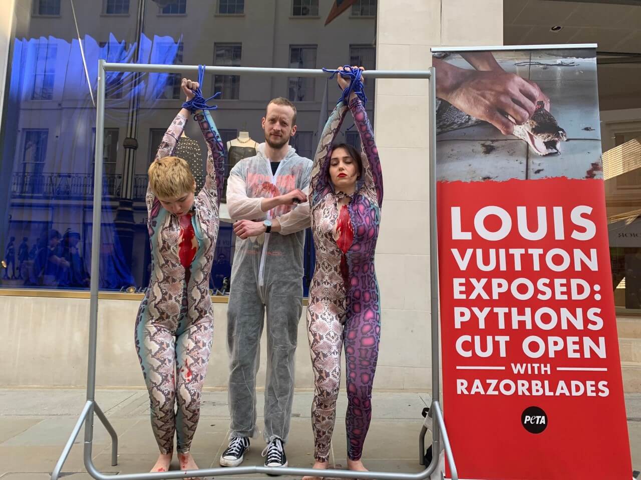 London, UK. 23rd March 2022. PETA activists wearing snake costumes and  covered in fake blood were 'skinned alive' outside the Louis Vuitton store  in New Bond Street in protest against the use