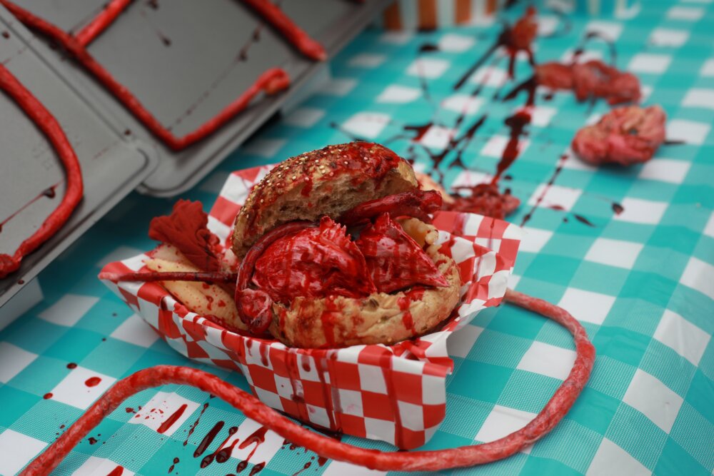 A takeaway box containing a fake chicken head, blood, and guts
