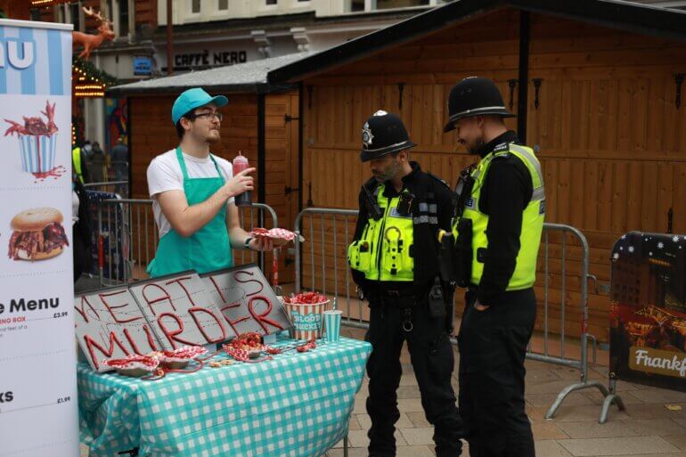 An activist speaking to two policemen during a chicken shop demonstration in Birmingham