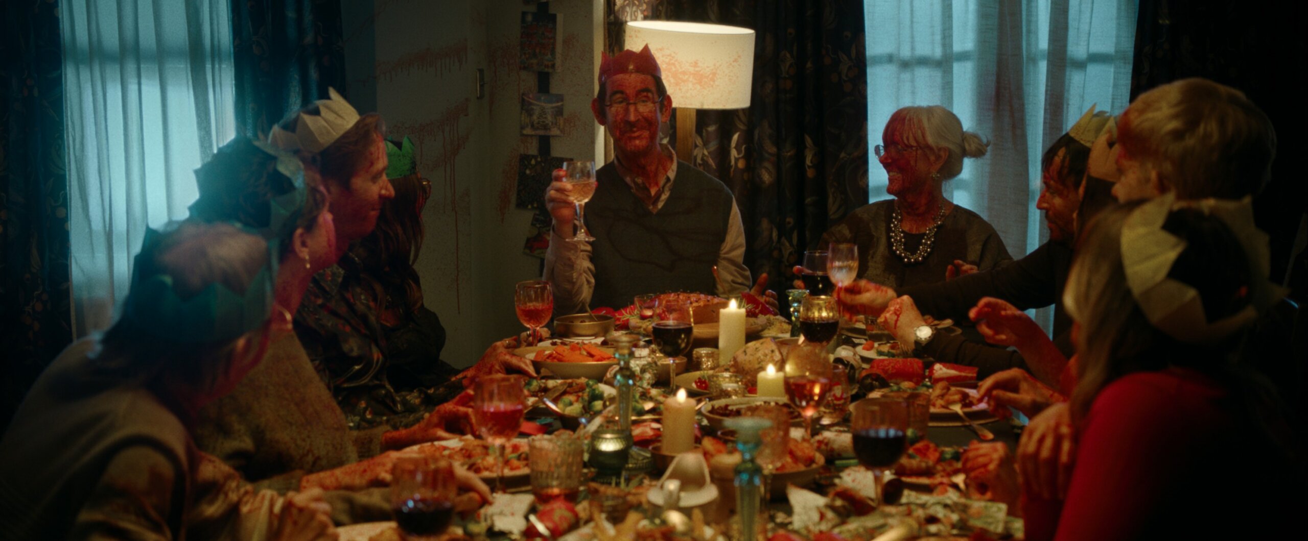 A family sitting round a Christmas table covered in fake blood