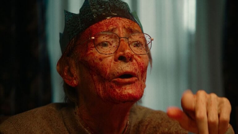 A still from the PETA Christmas advert 2025 showing an old man with fake blood on his face in a Christmas hat