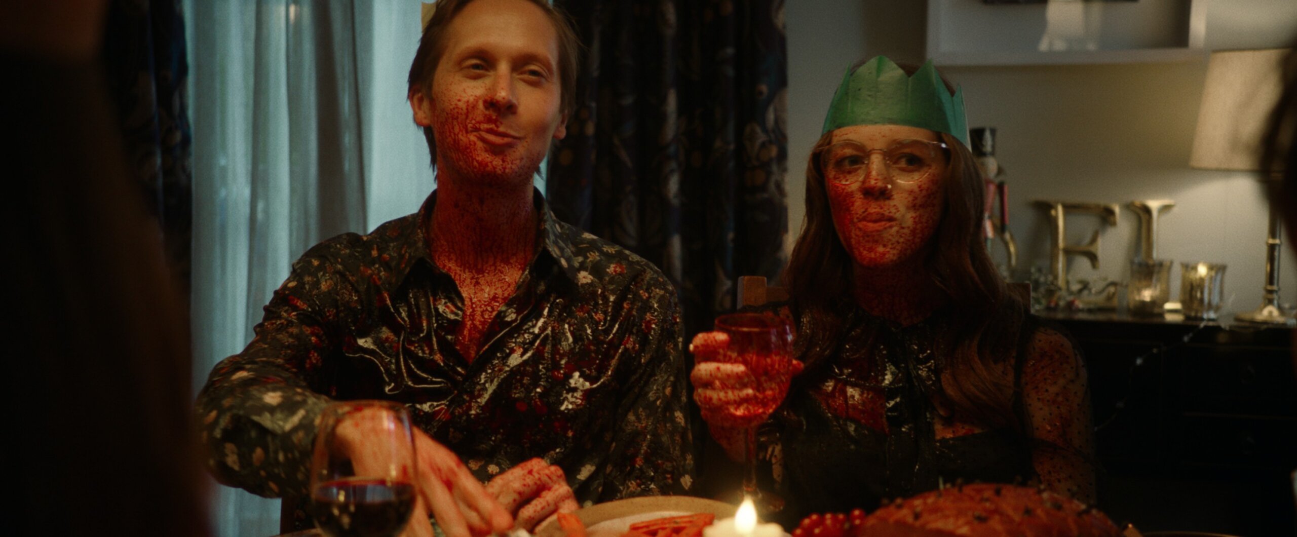 A family sitting round a Christmas table covered in fake blood