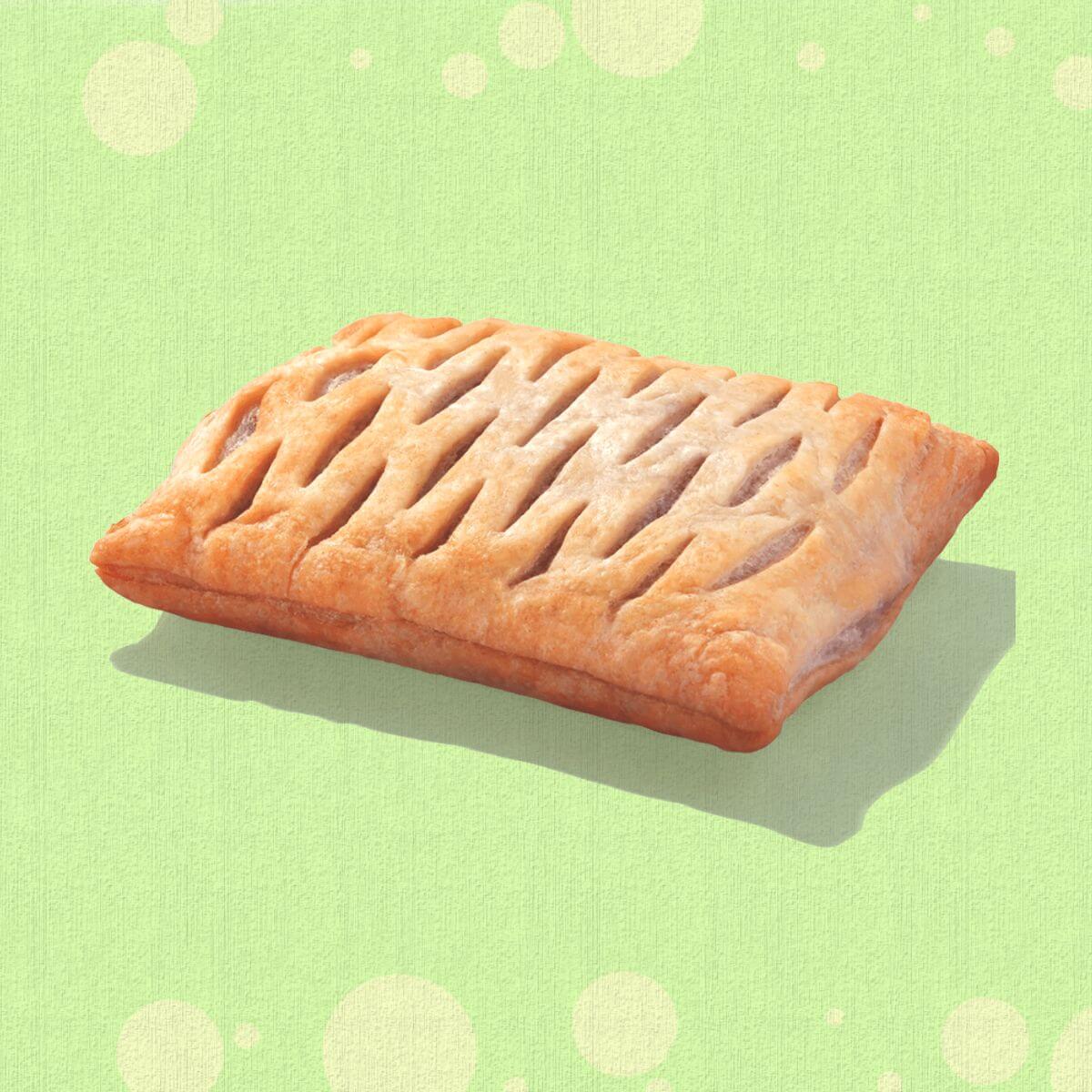 A Greggs vegan sausage roll in front of a green background