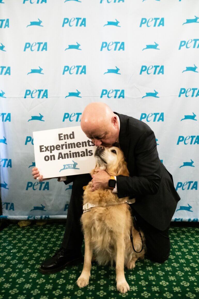 Steve Darling, MP cuddling a dog and holding a banner stating "End Experiments on Animals