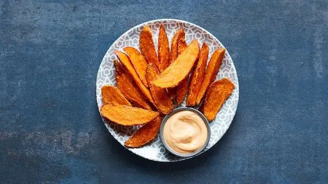 A plate of sweet potato wedges with Garlic PERinaise from the Nando's vegan menu