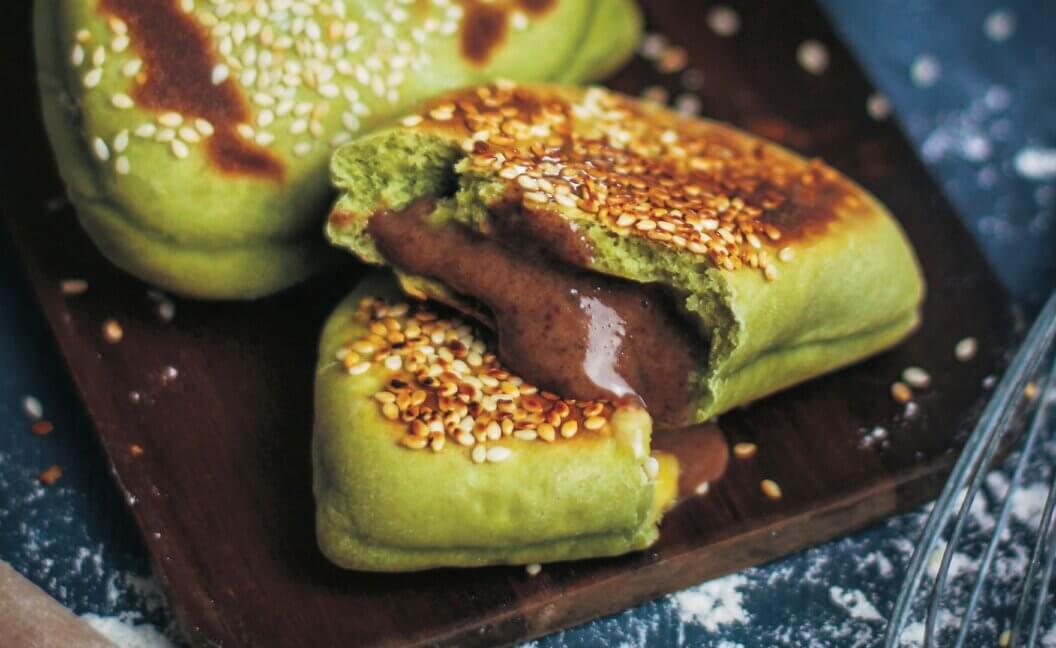 A close up of green matcha buns with chocolate custard oozing out of them