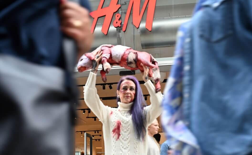 A PETA activists holding up a fake dead lamb outside an H&M store