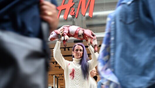 A PETA activists holding up a fake dead lamb outside an H&M store